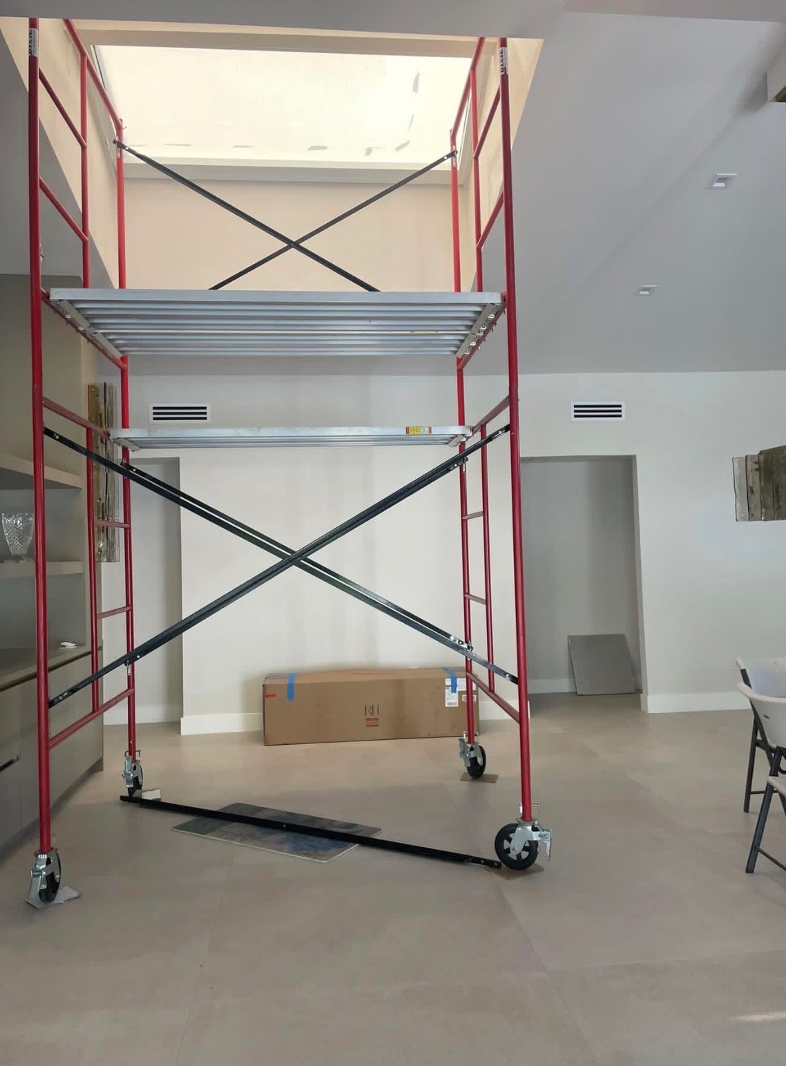 Red mobile scaffold tower set under a high interior ceiling